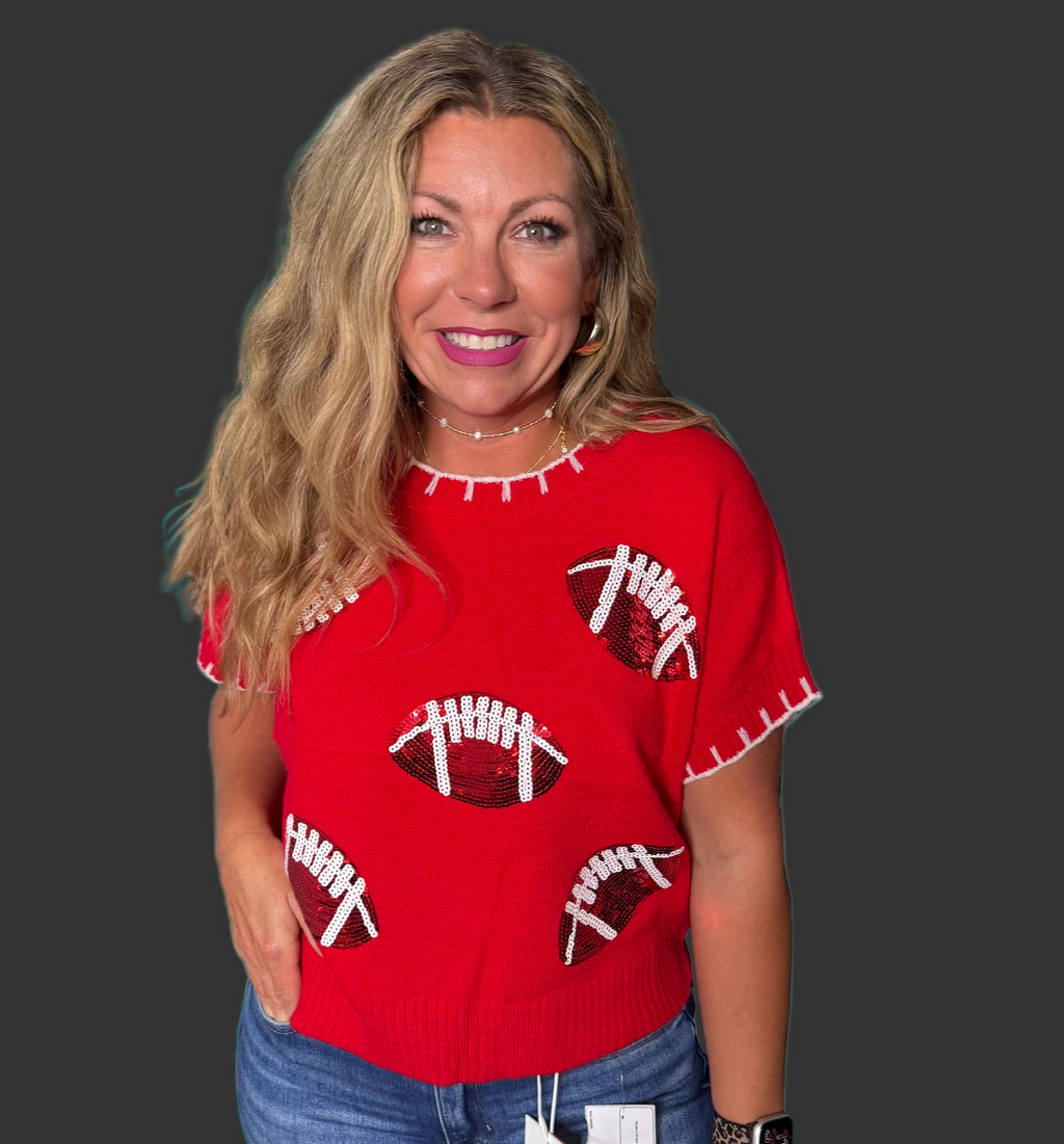 Woman wearing a red sweater with football patterns on a plain background