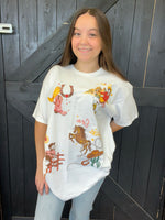 Person wearing a white t-shirt with colorful graphics in front of a wooden door.