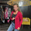 Woman in a red cardigan standing in front of a clothing rack with a 'Country Lace' sign in the background.