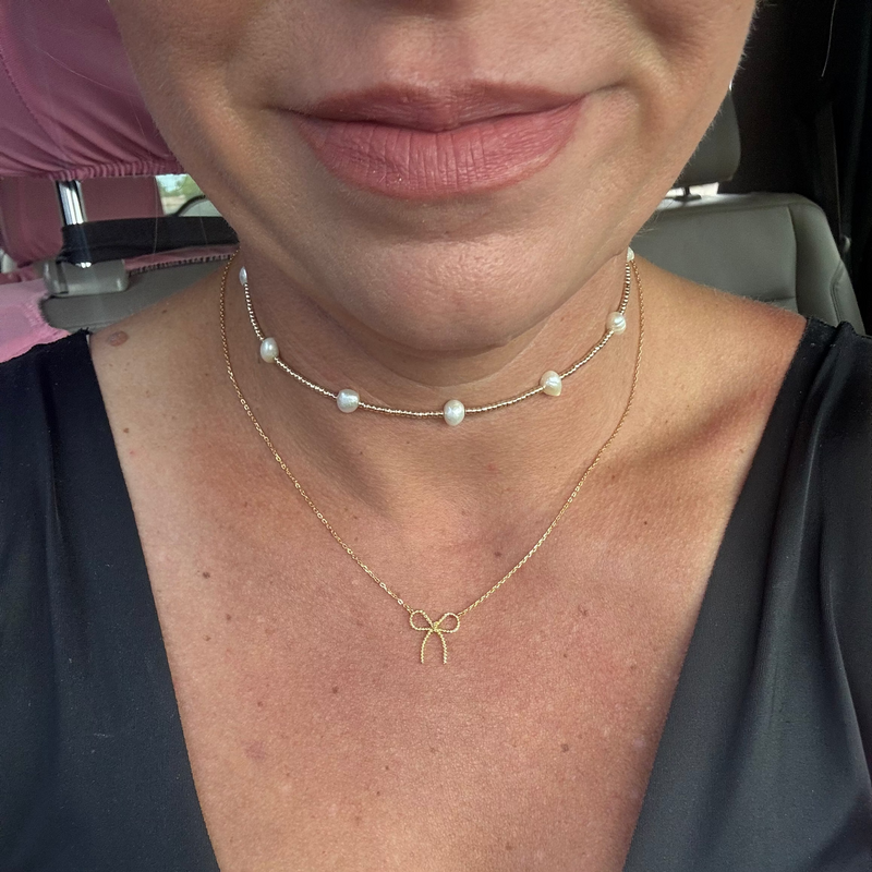 Close-up of a person wearing two necklaces with a blurred background