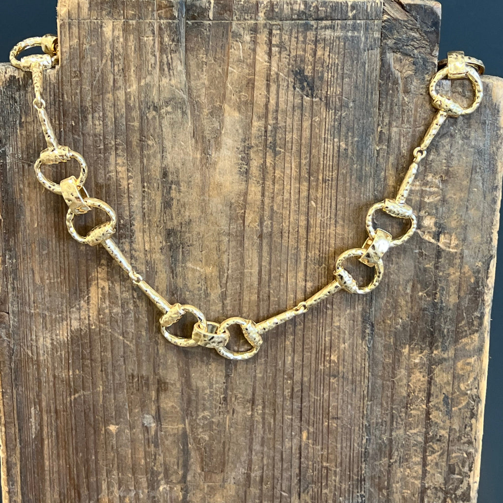 Gold chain bracelet on a wooden surface with a dark blue background
