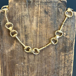 Gold chain bracelet on a wooden surface with a dark blue background