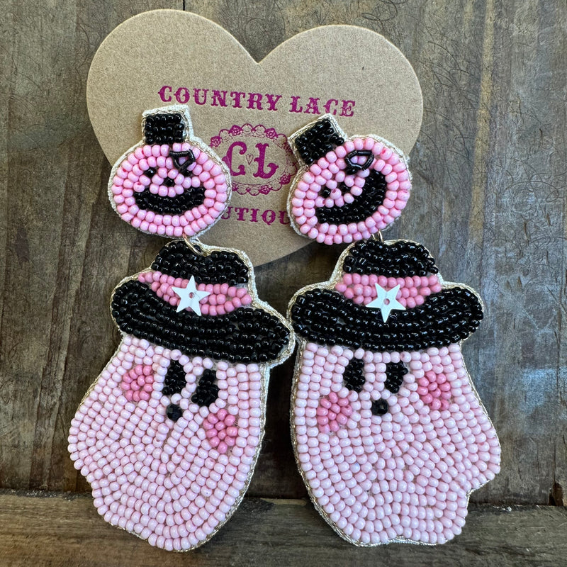 Beaded ghost earrings with pink and black details on a wooden background