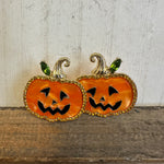 Pair of jack-o'-lantern earrings on a wooden surface with a neutral background
