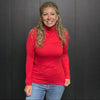 Woman in a red turtleneck standing in front of a clothing rack and 'Country Ace' sign.