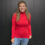 Woman in a red turtleneck standing in front of a clothing rack and 'Country Ace' sign.