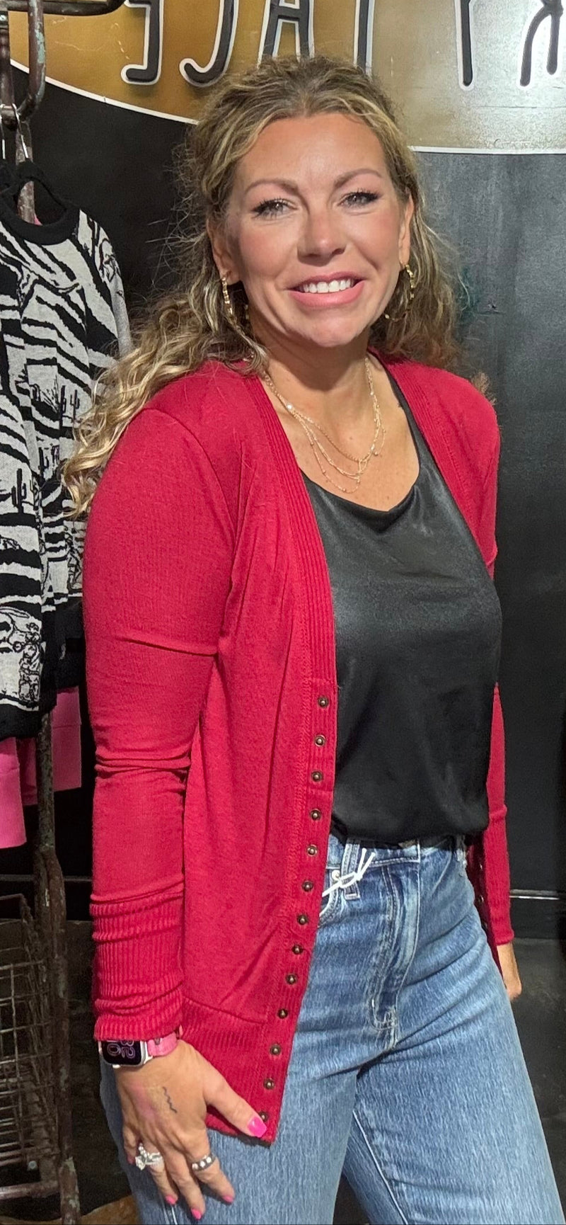 Woman standing in a store with clothing racks and a yellow chair in the background.