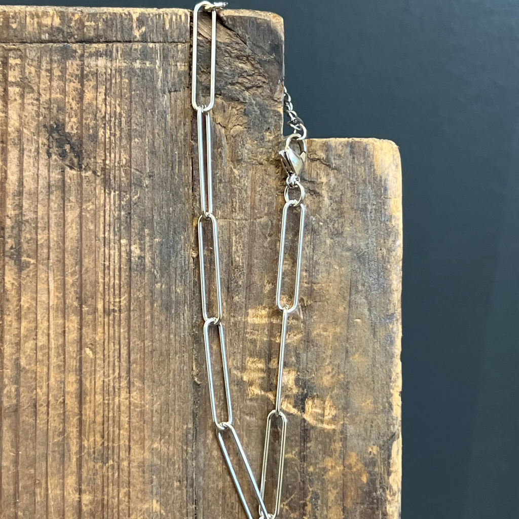 Silver chain necklace on a wooden block with a dark background