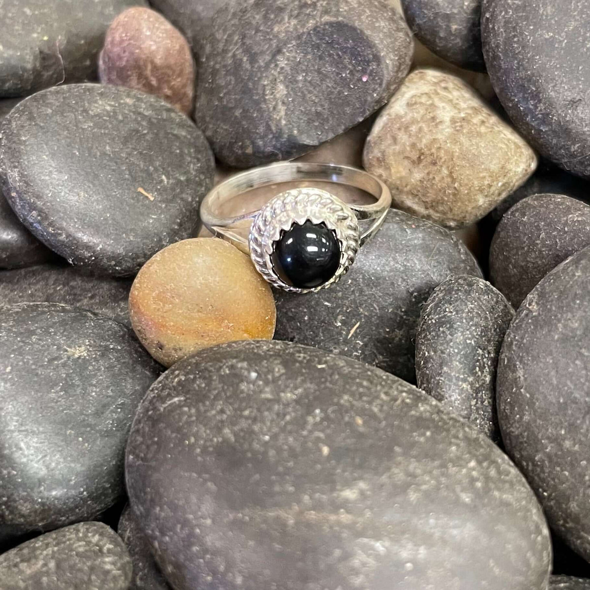 A sterling silver ring with a round onyx centerpiece, surrounded by smaller onyx stones