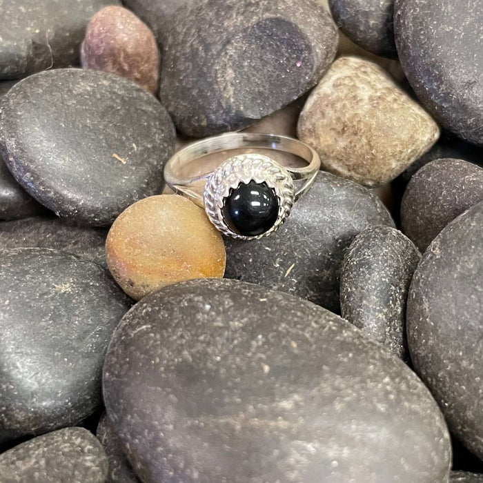A sterling silver ring with a round onyx centerpiece, surrounded by smaller onyx stones